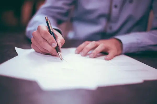 Ręka pisze na papierze, wypełniając dokumenty dotyczące podatku od spadku po wujku.
